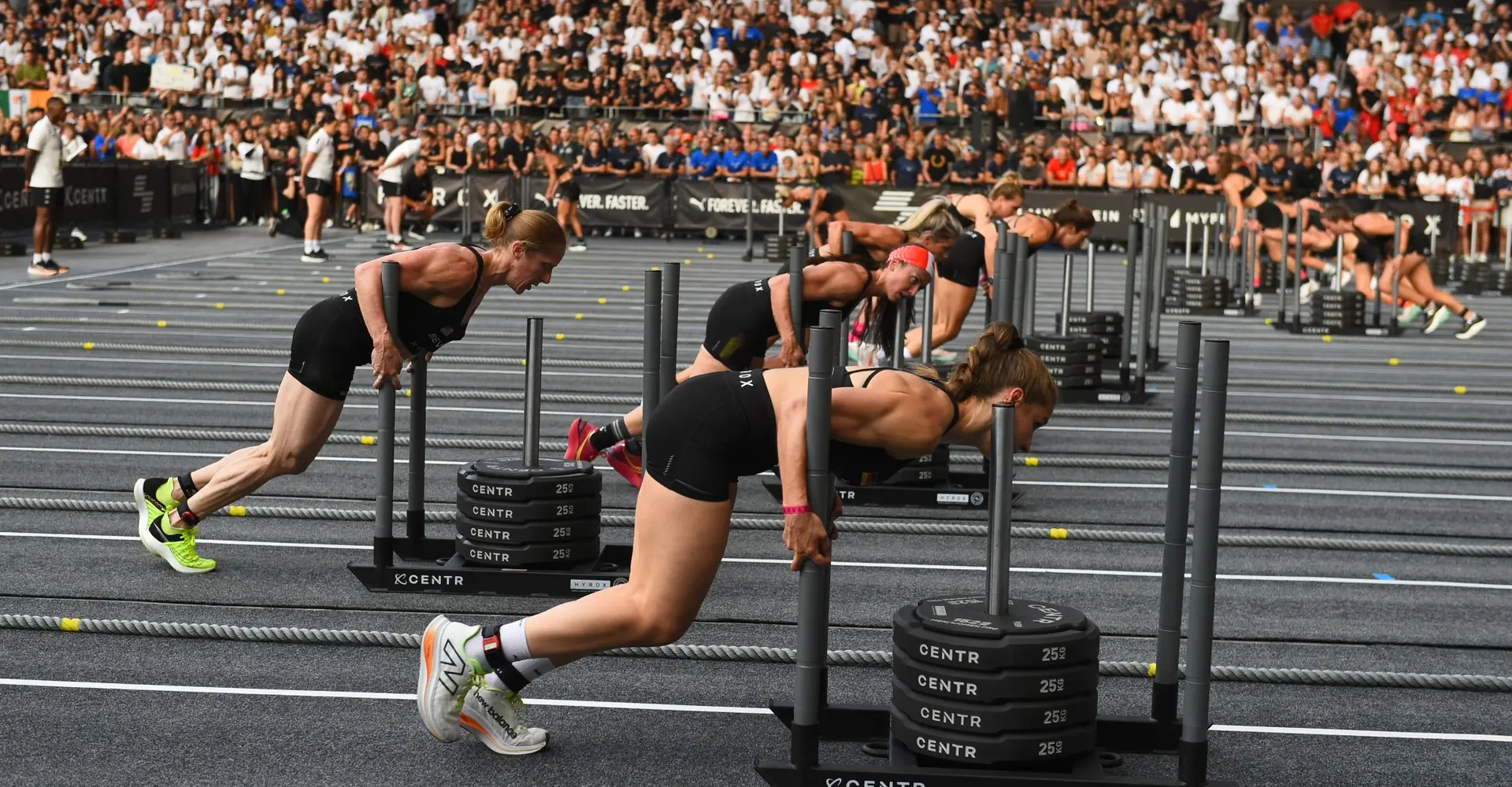 Atletas no sled push durante uma prova HYROX