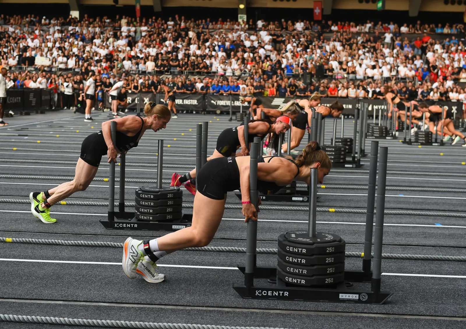 Atletas no sled push em prova HYROX
